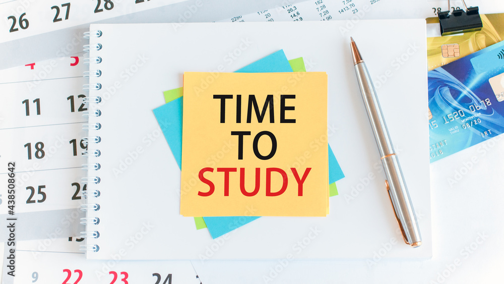 Poster time to study, the text is written on yellow paper lying on a white notepad on the desktop of an off