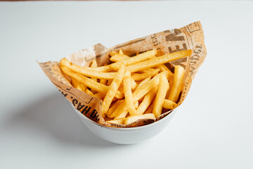 View on freshly fried fries in bowl on bright backgroud