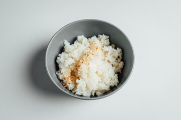 White rice with sesam in grey bowl on bright background