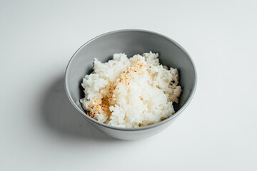White rice with sesam in grey bowl on bright background