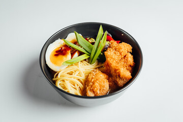 Ramen soup with fried chicken and egg on bright background