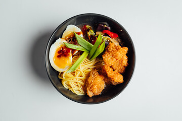 Ramen soup with fried chicken and egg on bright background