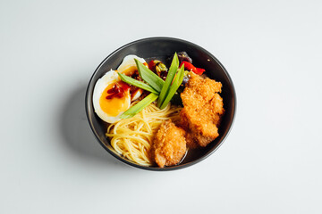 Ramen soup with fried chicken and egg on bright background