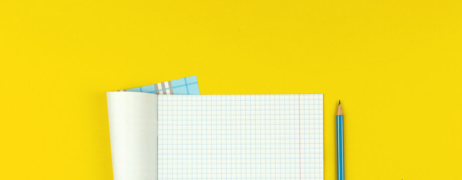 Education Banner With Opened School Notebook With Checkered Math Paper And Pencil On Yellow Table Background, Copy Space And Top View Photo