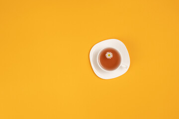 Cup of tea with flowers isolated on yellow background top view with workspace for text	