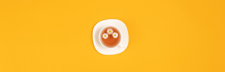 Cup of tea with flowers isolated on yellow background top view with copy space for text