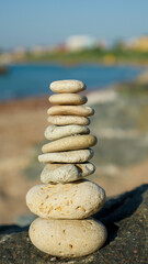 Fototapeta na wymiar Stone pyramid on sea stone coast near to sand beach. Holidays vacation sightseeing. Stack of stones