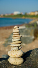 Fototapeta na wymiar Balanced stone pyramid on sand on beach. Holidays vacation sightseeing. 