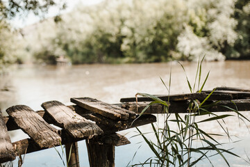 Old Damaged Wooden Bridge Over River Leading Towards Forest