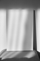 White canvas mockup on shelf on wall with shadows. Blank picture. Stretched canvas
