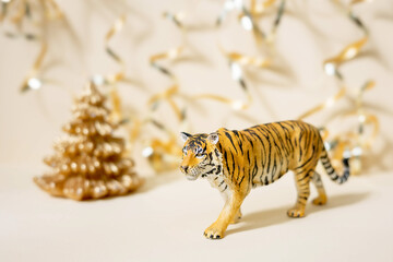 Tiger symbol of the Chinese new year 2022. Figurine of tiger with golden christmas fir tree on pastel background. Copy space.