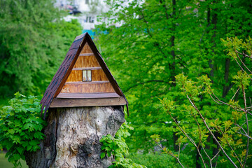 house in the forest for animals and birds. Wooden bird house in the summer park. on an tree stump. Old wooden feeder for birds on a tree, empty bird's feeder caring about wild birds in cold season.