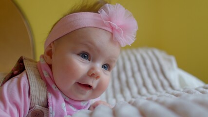 Portrait of a toddler girl in joy. A flower is worn on his head. She looks around, the time the child is awake. Blue eyes.