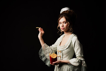 charming woman in vintage pastel grey dress posing with french fries isolated on black