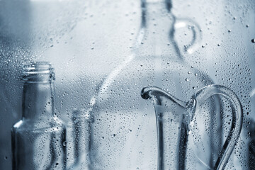 Carafe for water. Glass transparent bottles in water drops. Glass dishes.