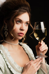 charming woman in elegant vintage outfit holding glass of white wine isolated on black