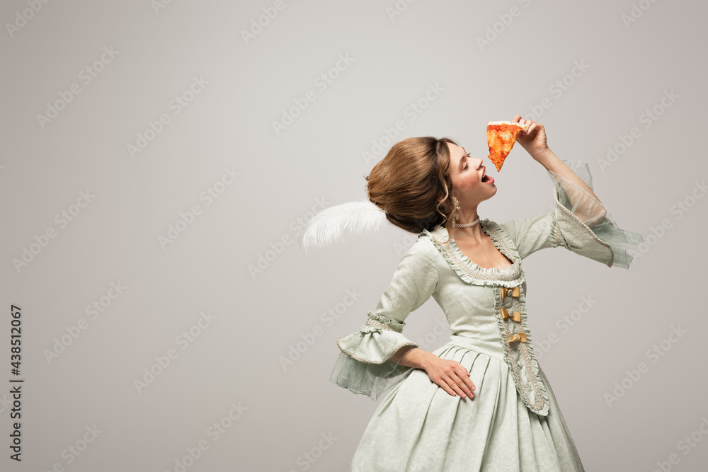 Wall mural stylish woman in retro clothing eating delicious pizza with closed eyes isolated on grey