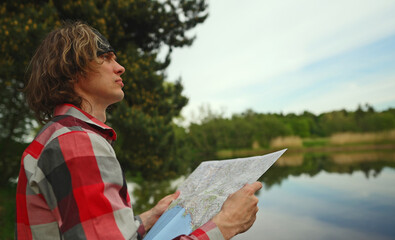 Male tourist with map by the lake.