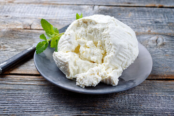 Fresh Italian ricotta with mint leaves served as close-up on a modern design plate