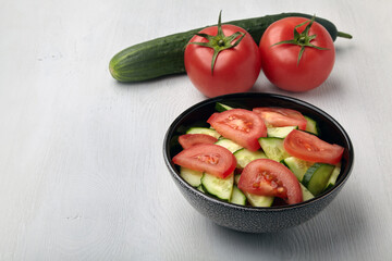 Fresh tomato and cucumber salad in dark bowl