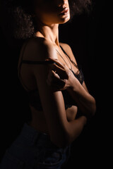 Cropped view of african american woman taking off bra isolated on black