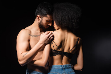 African american woman in bra hugging muscular boyfriend isolated on black