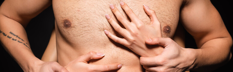 Cropped view of woman touching torso of tattooed boyfriend isolated on black, banner