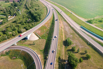 Aerial view of road interchange or highway intersection with busy urban traffic speeding on the road
