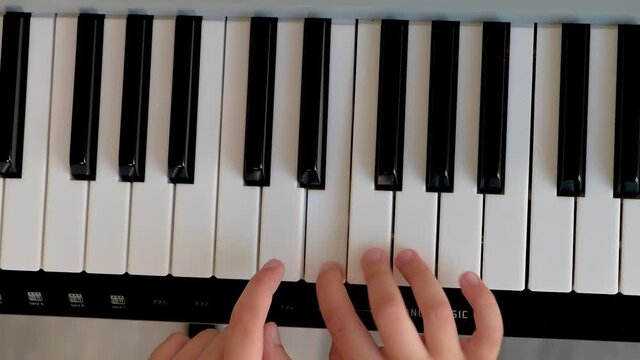 Selective focus of kid's fingers playing the piano. There are musical instrument for concert or learning music. Close up hand of child musician playing the piano
