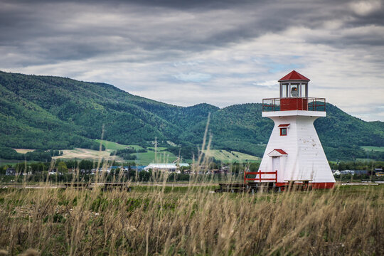 View on the small but cute Carleton's lighthouse with a view on the Mount St Joseph in the background, located in Quebec, Canada