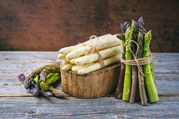 Raw green, white and violet asparagus in vintage cinematic look offered as close-up on on an old...