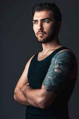 Portrait of brunette handsome man in studio. Guy with lion tattoo on his arm on black background