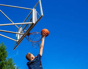 Young red-haired guy throws a ball into a basketball hoop