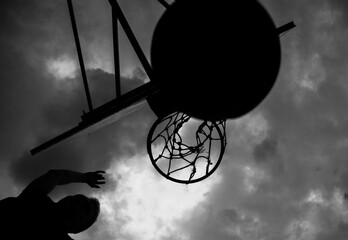 Silhouette of a man who throws a ball into a basketball hoop