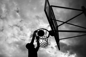 Silhouette of a man who throws a ball into a basketball hoop