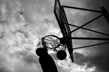 Silhouette of a man who throws a ball into a basketball hoop