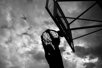Silhouette of a man who throws a ball into a basketball hoop