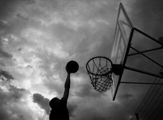 Silhouette of a man who throws a ball into a basketball hoop