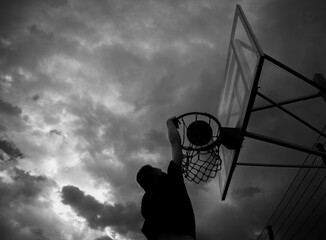 Silhouette of a man who throws a ball into a basketball hoop