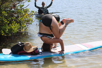 woman doing headstand in open water with other woman watching