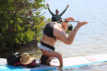 woman doing headstand in open water with other woman watching