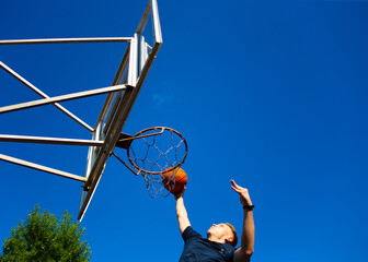 Young red-haired guy throws a ball into a basketball hoop