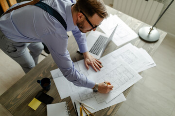 Top view of architects writing and working with blueprints.