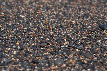 Abstract background with black and orange round sea pebble stones texture on the shore close up in the blurry sunset light, close up, natural copy space .