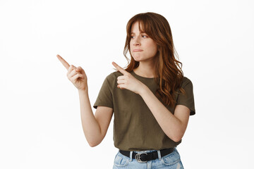 Disappointed girl feels regret or jealous, pointing fingers and looking left with unfair pout,...