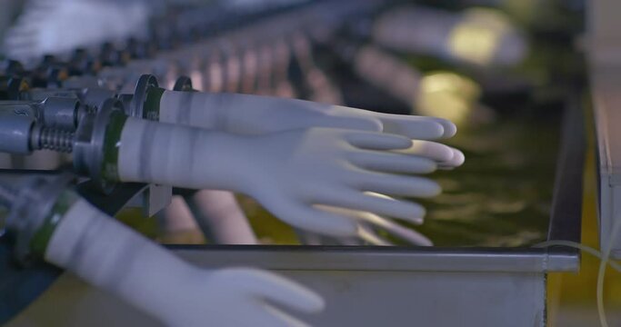 Close-up, treatment of rubber gloves with a special solution on the conveyor. Modern equipment at the nitrile rubber glove factory. 4k, ProRes