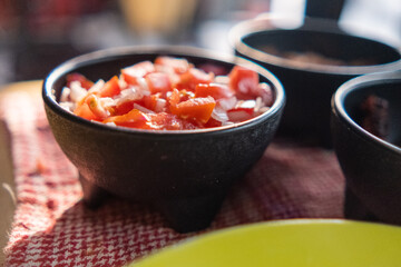 Black bowls of pico de gallo above checkered tablecloth