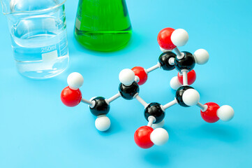 Organic chemistry, scientific experiment and analyze molecular structure concept with teaching plastic model molecule, beaker and other lab glassware isolated on blue background