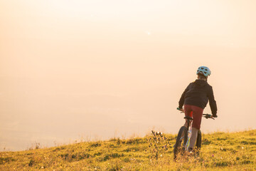 Girl child riding mountain bike into the sunset. Beautiful golden summer light.