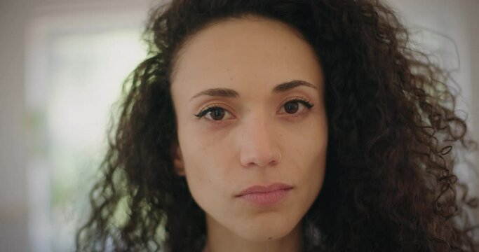 Portrait of a serious looking multi ethnic young woman looking ti the camera. Close up, slow motion. 